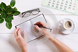 Top view female hand writes list makes notes