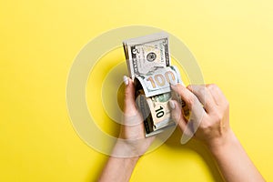 Top view of female hands counting money. One hundred and other dollar banknotes on colorful background. Business concept