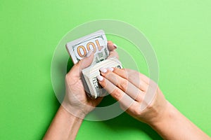 Top view of female hands counting money. One hundred and twenty dollar banknotes on colorful background. Salary concept. Bribe