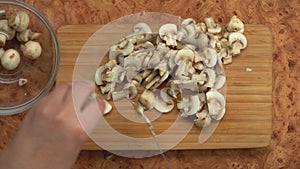 Top view of the female hands cutting champignon mushrooms into the slices