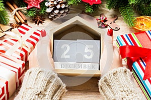 Top view of female hands holding a calendar on wooden background. The twenty fifth of December. Holiday decorations. Christmas