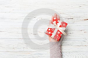 Top view of female hands holding christmas or other holiday handmade present box package in the palms, flat lay table background