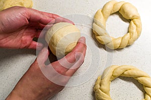 Top view of female hands preparing dough on white kitchen table