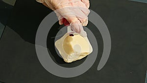 Top view on female hands put cube of white marzipan mass and red colorant on it