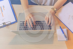 Top view of female hands typing on laptop keyboard