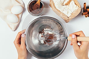 Top view of female hands whisk flour and cocoa powder