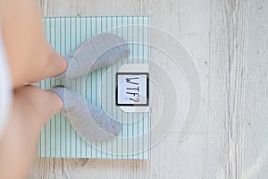 Top view on female legs in gray socks on electronic scales. Very heavy weight. The surprise of the increase in kg on a