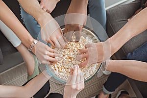 top view of female and male hands taking popcorn