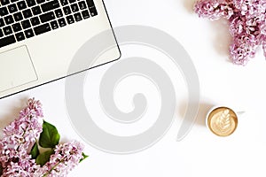 Top view of female worker desktop with laptop, flowers and different office supplies items. Feminine creative design workspace.
