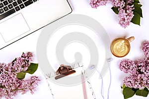 Top view of female worker desktop with laptop, flowers and different office supplies items. Feminine creative design workspace.