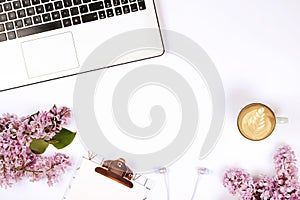 Top view of female worker desktop with laptop, flowers and different office supplies items. Feminine creative design workspace.