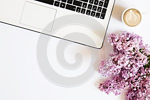 Top view of female worker desktop with laptop, flowers and different office supplies items. Feminine creative design workspace.