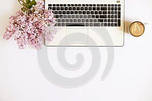 Top view of female worker desktop with laptop, flowers and different office supplies items. Feminine creative design workspace.