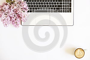 Top view of female worker desktop with laptop, flowers and different office supplies items. Feminine creative design workspace.