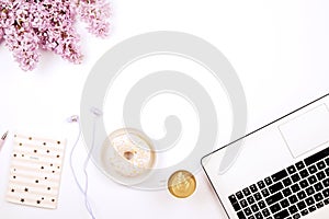 Top view of female worker desktop with laptop, flowers and different office supplies items. Feminine creative design workspace.