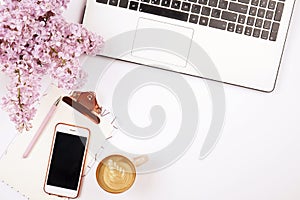 Top view of female worker desktop with laptop, flowers and different office supplies items. Feminine creative design workspace.