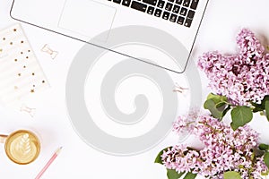 Top view of female worker desktop with laptop, flowers and different office supplies items. Feminine creative design workspace.