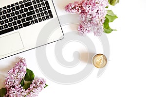 Top view of female worker desktop with laptop, flowers and different office supplies items. Feminine creative design workspace.