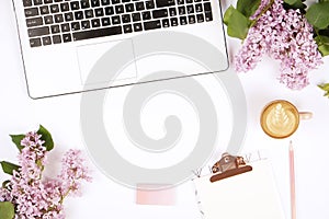 Top view of female worker desktop with laptop, flowers and different office supplies items. Feminine creative design workspace.