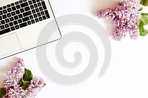 Top view of female worker desktop with laptop, flowers and different office supplies items. Feminine creative design workspace.