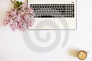 Top view of female worker desktop with laptop, flowers and different office supplies items. Feminine creative design workspace.