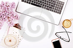 Top view of female worker desktop with laptop, flowers and different office supplies items. Feminine creative design workspace.