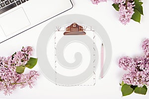 Top view of female worker desktop with laptop, flowers and different office supplies items. Feminine creative design workspace.