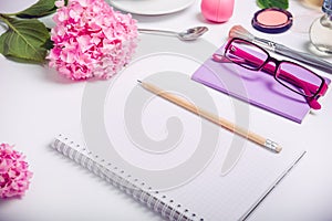 Top view Female working place with notebook for planning, cosmetic accessories, sketchbook, glasses, and wisteria flowers on the w photo