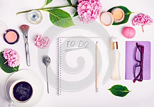 Top view Female working place with To do list, cosmetic accessories, cup of coffee, notebook, glasses, and wisteria flowers. Day p