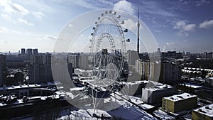 Top view of Ferris wheel in city center in winter. Creative. Large Ferris wheel stands in city on sunny winter day. Non