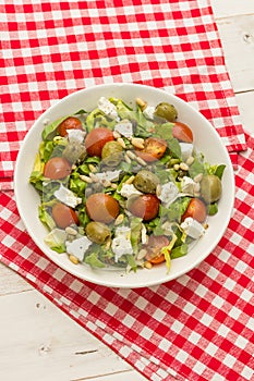 Top view of a fesh sald with lettuce, cherry tomatoes, green olives and greek feta