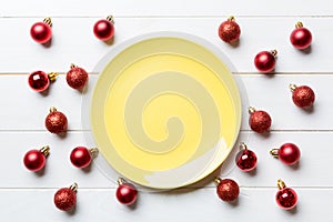 Top view of festive plate with red baubles on wooden background. Christmas decorations and toys. New Year advent concept