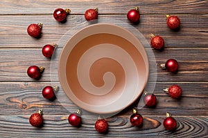 Top view of festive plate with red baubles on wooden background. Christmas decorations and toys. New Year advent concept
