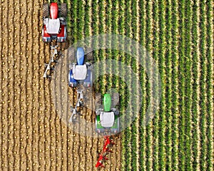 Top view on a field where three tractors with plows cultivate the ground one after another,