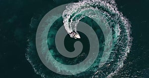 Top view figure of circle and spiral shape made with foamy speedboat traces on azure ocean water surface