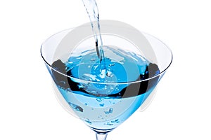 Top of view of filling a glass with blue cocktail tilted and bubbles