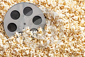 top view of film reel on delicious popcorn, cinema concept.