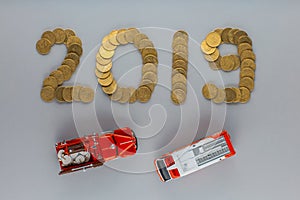 Top view of a fire engine figurine and an ambulance figurine under 2019 which is written with coins, on gray background