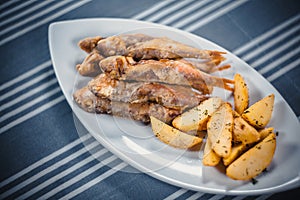 Top view of fish and chips. Fried fish and potato slices on a white plate. Plate on the table with a blue tablecloth in