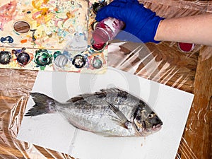 Top view of fish and pouring paint in palette