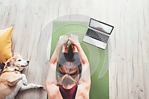 Top view at fit sporty healthy woman sit on mat in Paschimottanasana pose, doing breathing exercises, watching online yoga class