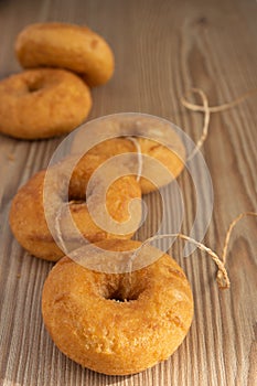 Top view of five donuts with a rope, on wooden board, with unfocused background