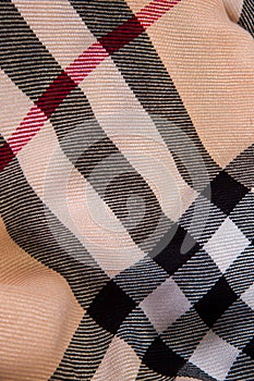 top view flat lay closeup on beige checked scarf with black, white, and red strips