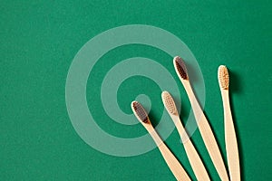 Top view or flat lay concept with eco bamboo tree toothbrushes on green background