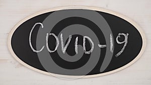 Top view flat lay of defeat and ward off the Coronavirus Covid-19 Pandemic concept. A woman`s hand writes Covid-19 in chalk and