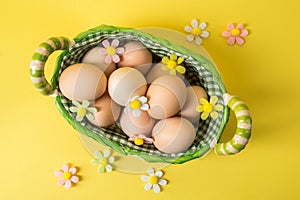 Top view, flat lay. Easter still life. Rustic brown eggs in a wicker basket lined with checkered fabric