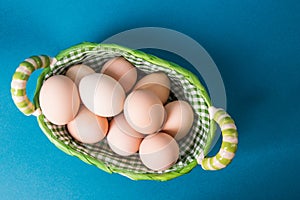 Top view, flat lay. Farm brown eggs in a wicker basket lined with checkered fabric. Copy space