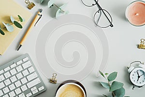 Top view, flat lay keyboard, cup of coffee, paper notebook, pen eucalyptus branches on office desk table. Elegant feminine