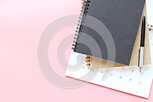 Top view or flat lay of notebooks, calendar and pen on pink background