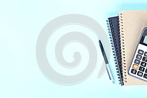 Top view or flat lay of notebooks, pen and calculator on blue background